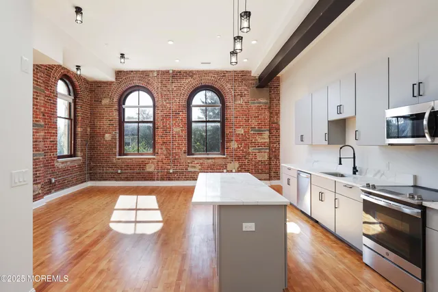 a large kitchen with stainless steel appliances granite countertop a large stove a sink dishwasher and white cabinets with wooden floor