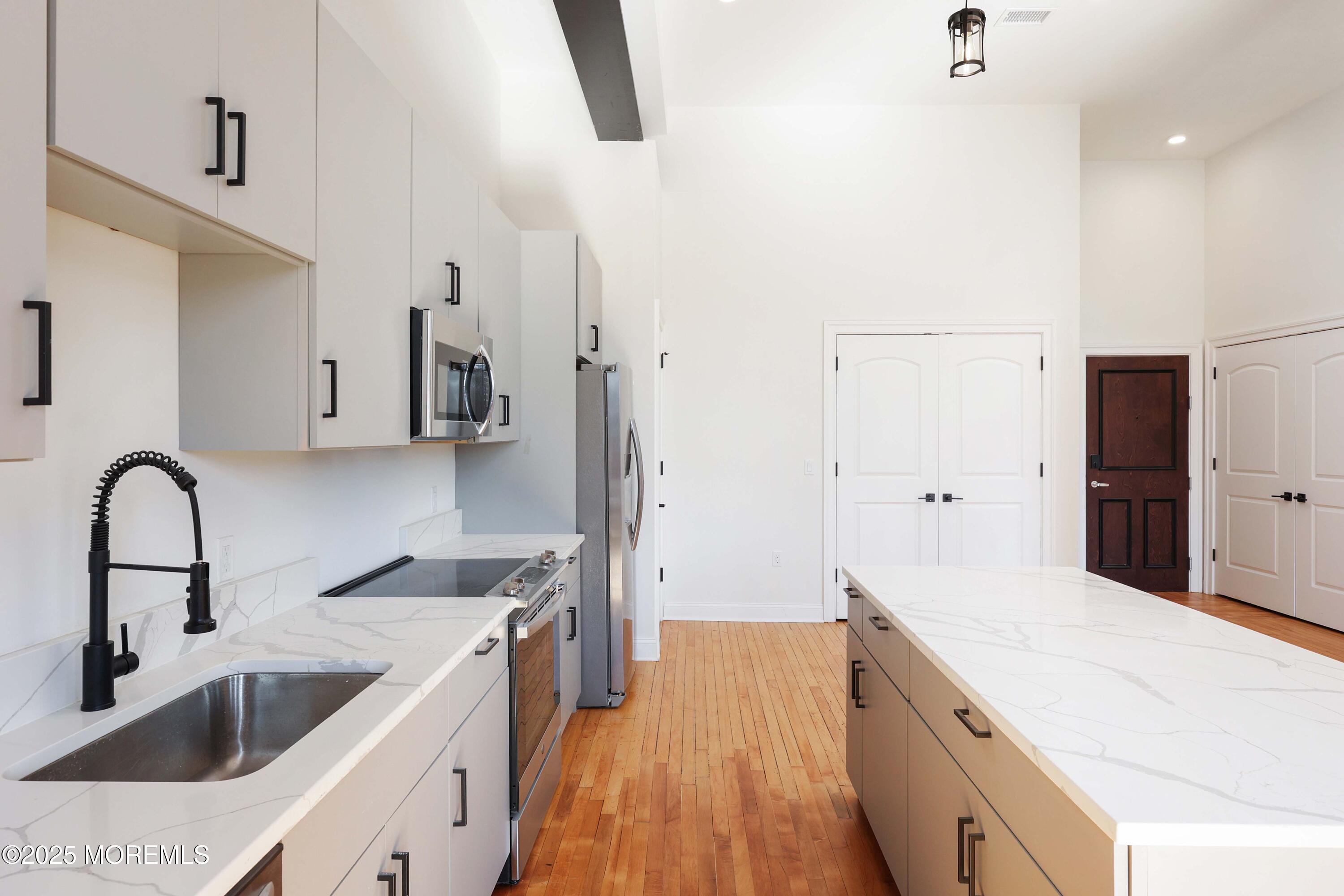 179 Chelsea Avenue, Unit 210 Long Branch, NJ 07740 - Photo 10 of 22 a large white kitchen with a stove a sink a refrigerator and cabinets
