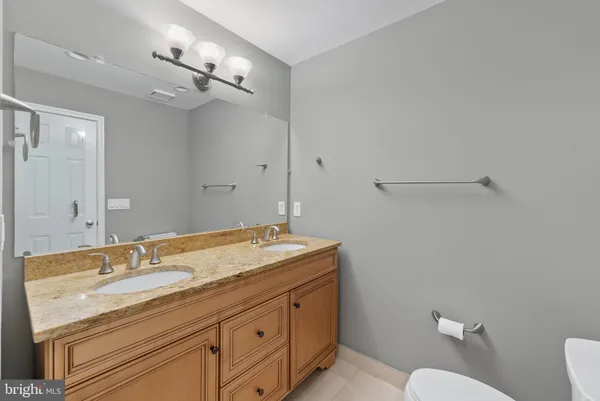 a bathroom with a granite countertop sink a toilet and a mirror