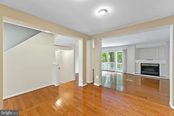 an empty room with wooden floor fireplace and windows