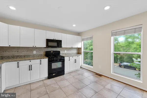 a kitchen with granite countertop white cabinets and stainless steel appliances