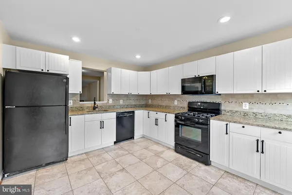 a kitchen with granite countertop white cabinets and stainless steel appliances