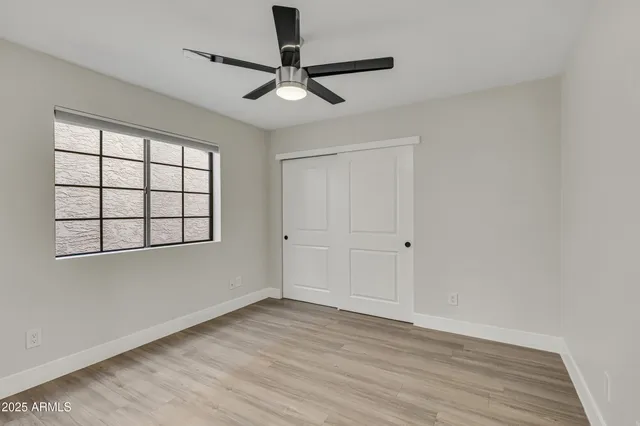 a view of an empty room with a window and wooden floor