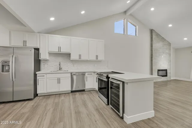 a kitchen with a sink a stove a refrigerator and white cabinets with wooden floor