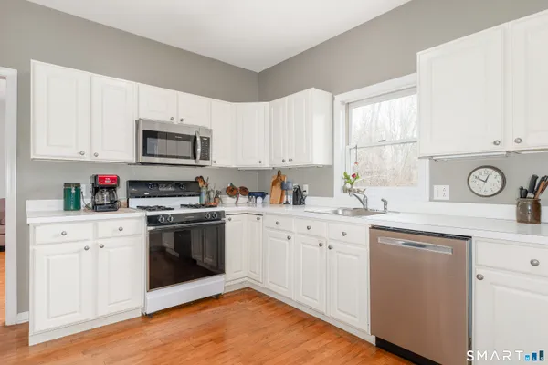 a kitchen with granite countertop a stove top oven a sink dishwasher and a refrigerator with wooden floor