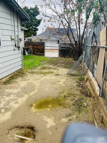 a view of a backyard with plants and large trees