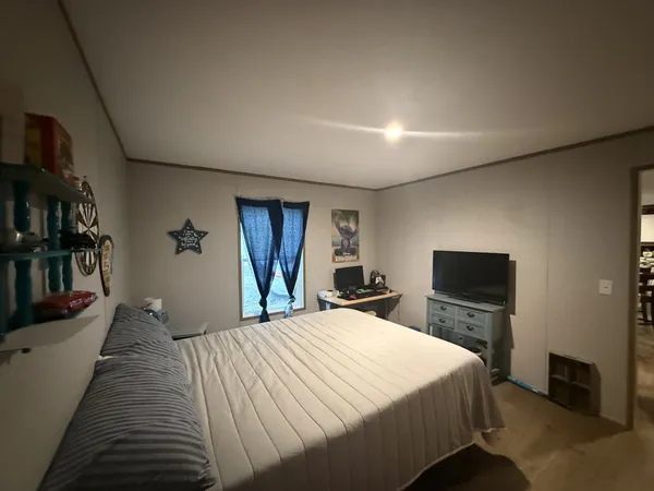 a bed sitting in a bedroom and a flat screen tv
