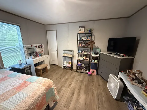 a bedroom with a bed and a flat tv screen on the dresser