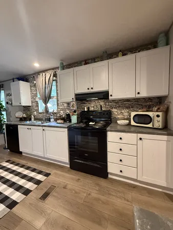 a kitchen with stainless steel appliances granite countertop a stove a sink and a white cabinets