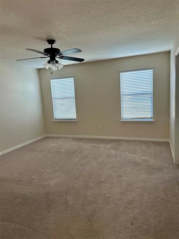an empty room with a window and a ceiling fan