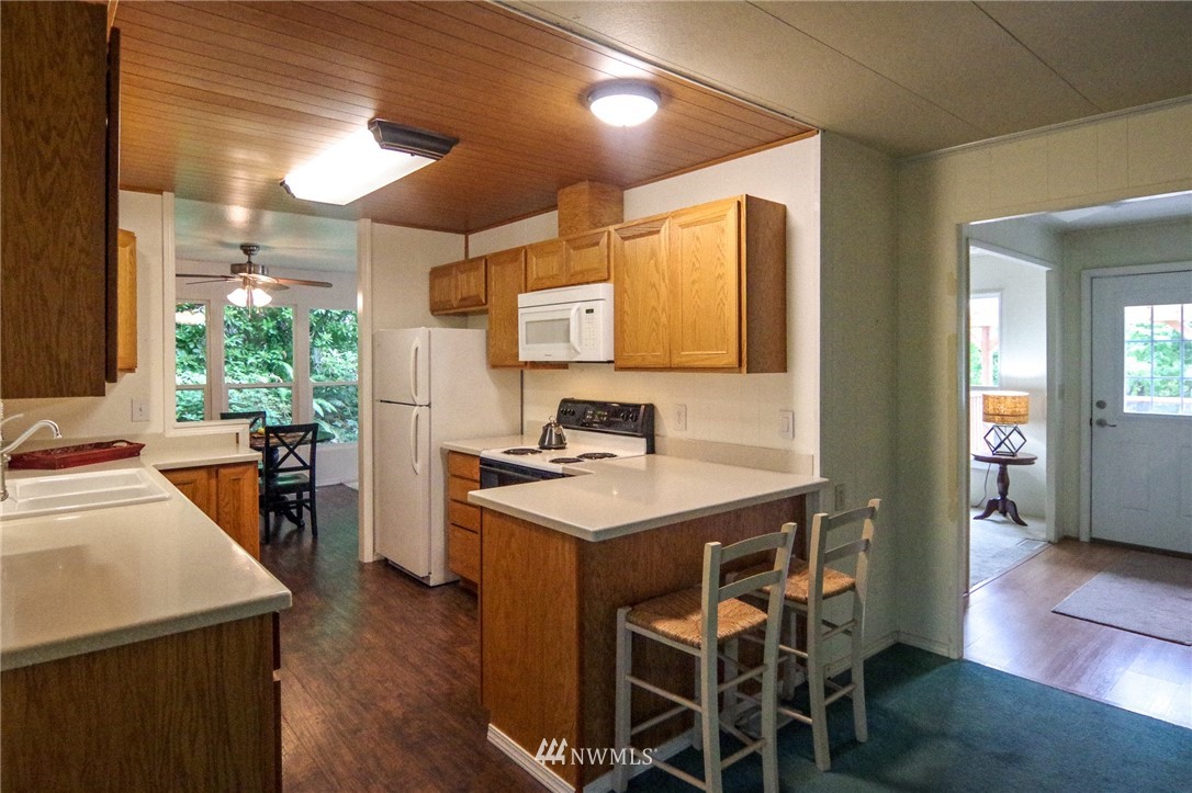 3309 206th Place Southeast Bothell, WA 98012 - Photo 12 of 32 a kitchen with a stove a sink refrigerator and a dining table with wooden floor