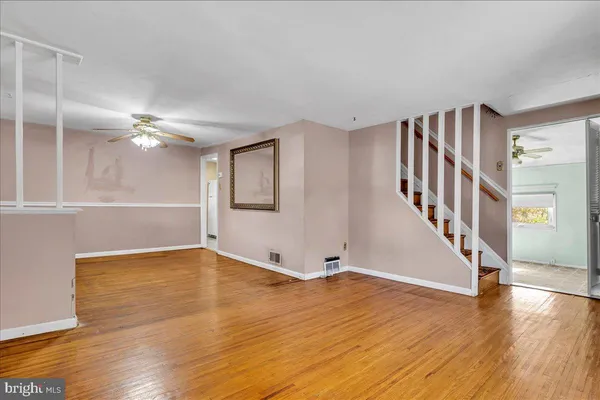 a view of an empty room with wooden floor and a ceiling fan