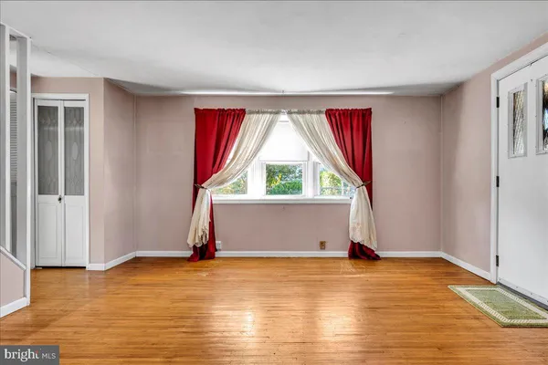 a view of an empty room with window and wooden floor
