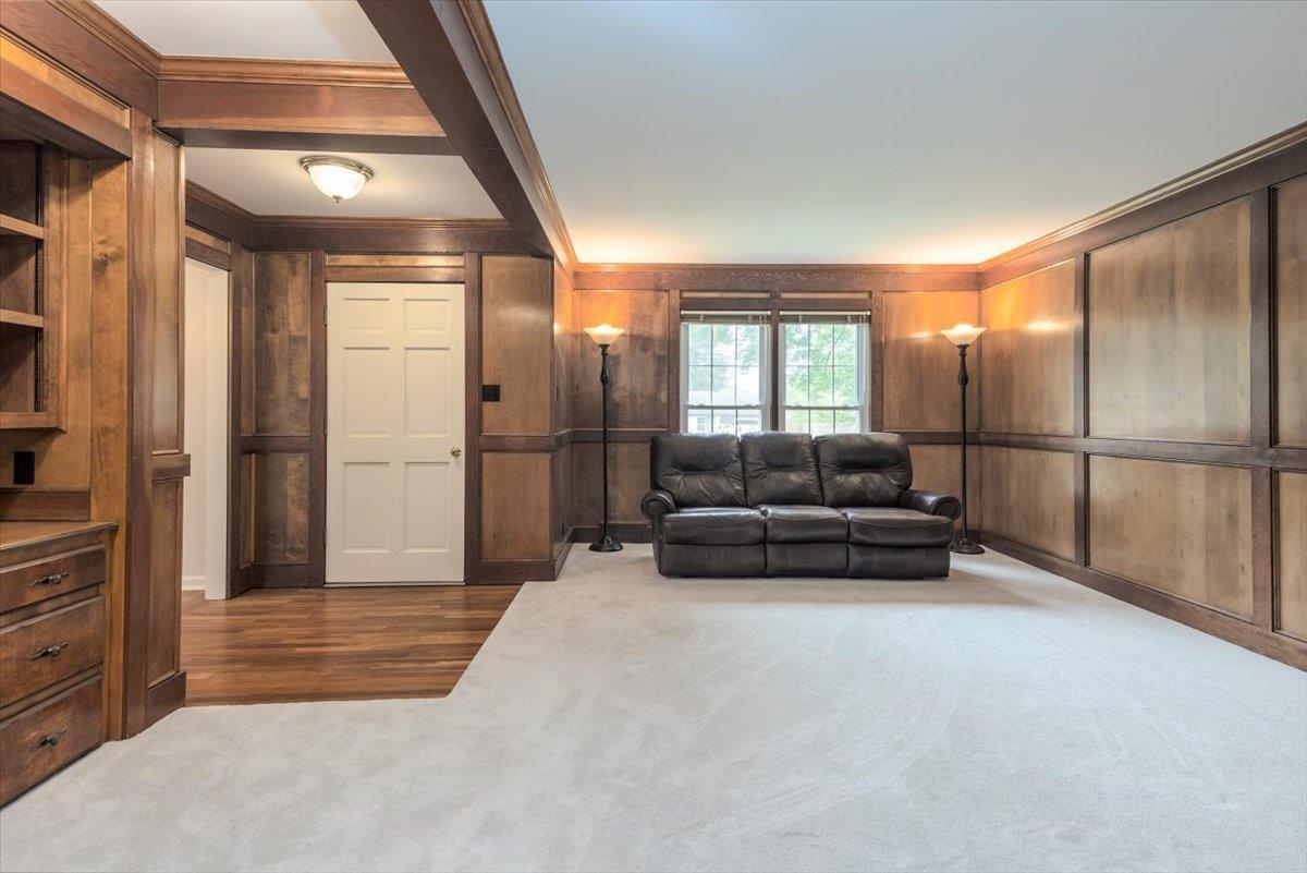 670 Peterson Lake Road Collierville, TN 38017 - Photo 12 of 37 Room featuring extensive wood paneling and trim, built-in shelving, wood-finish flooring, and light-toned carpeting