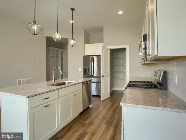 a kitchen with stainless steel appliances granite countertop a sink a stove and a refrigerator