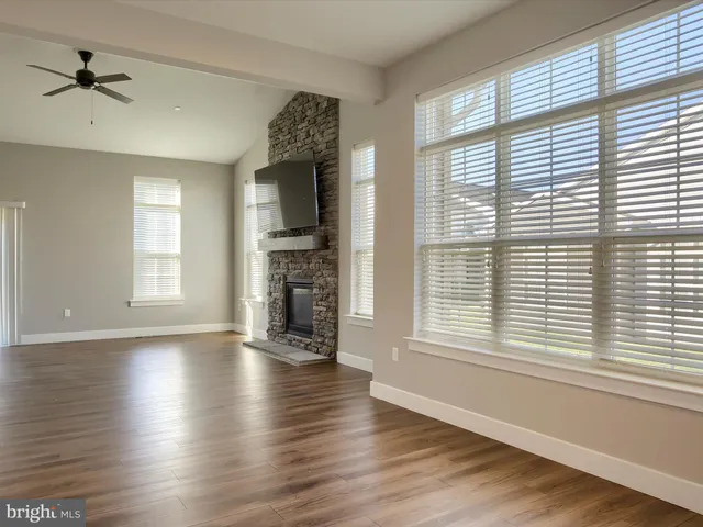 an empty room with wooden floor windows and a ceiling fan