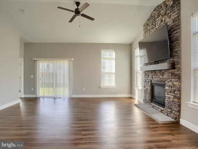 an empty room with windows a fireplace and wooden floor