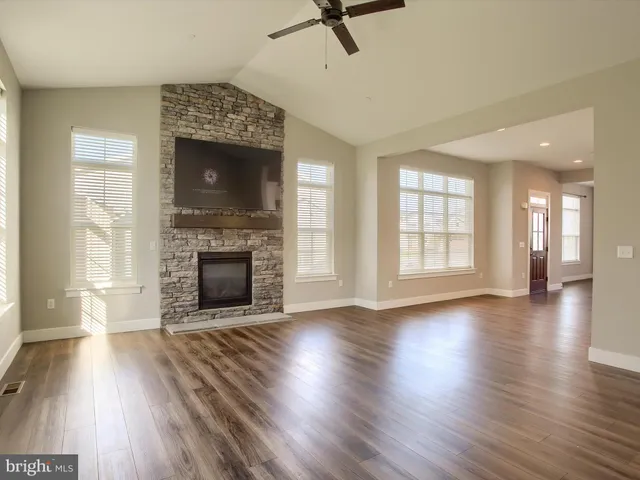 an empty room with wooden floor fireplace and windows