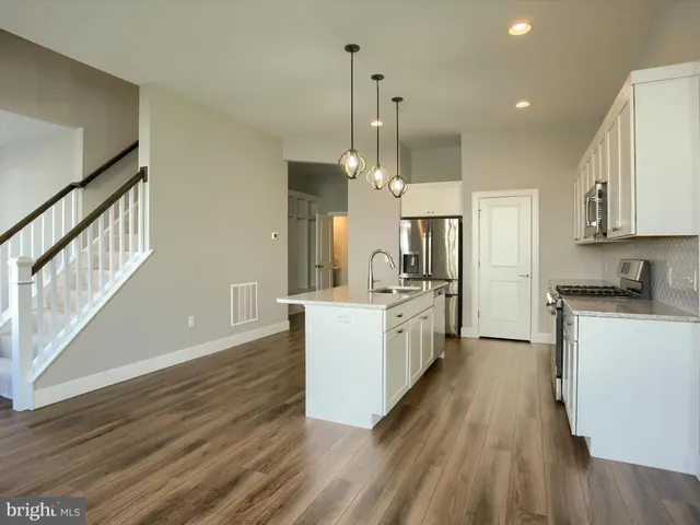 a large kitchen with a center island wooden floor stainless steel appliances and cabinets