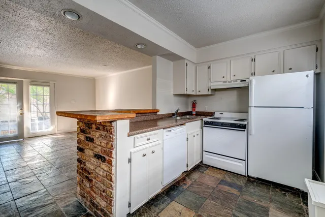 a kitchen with granite countertop a refrigerator sink and cabinets