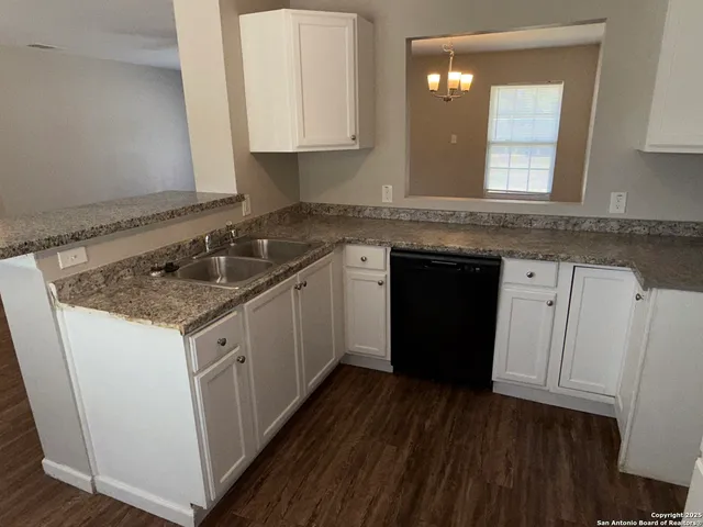 a kitchen with granite countertop a sink stove and cabinets