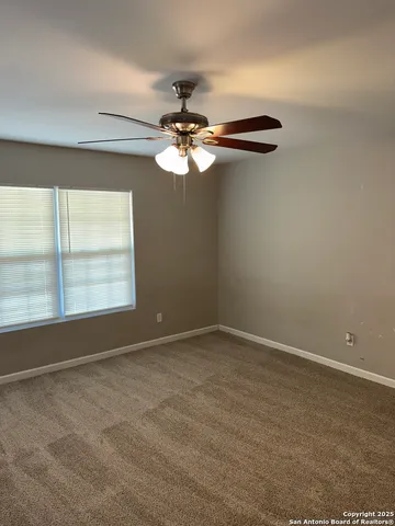 an empty room with a window and a fan
