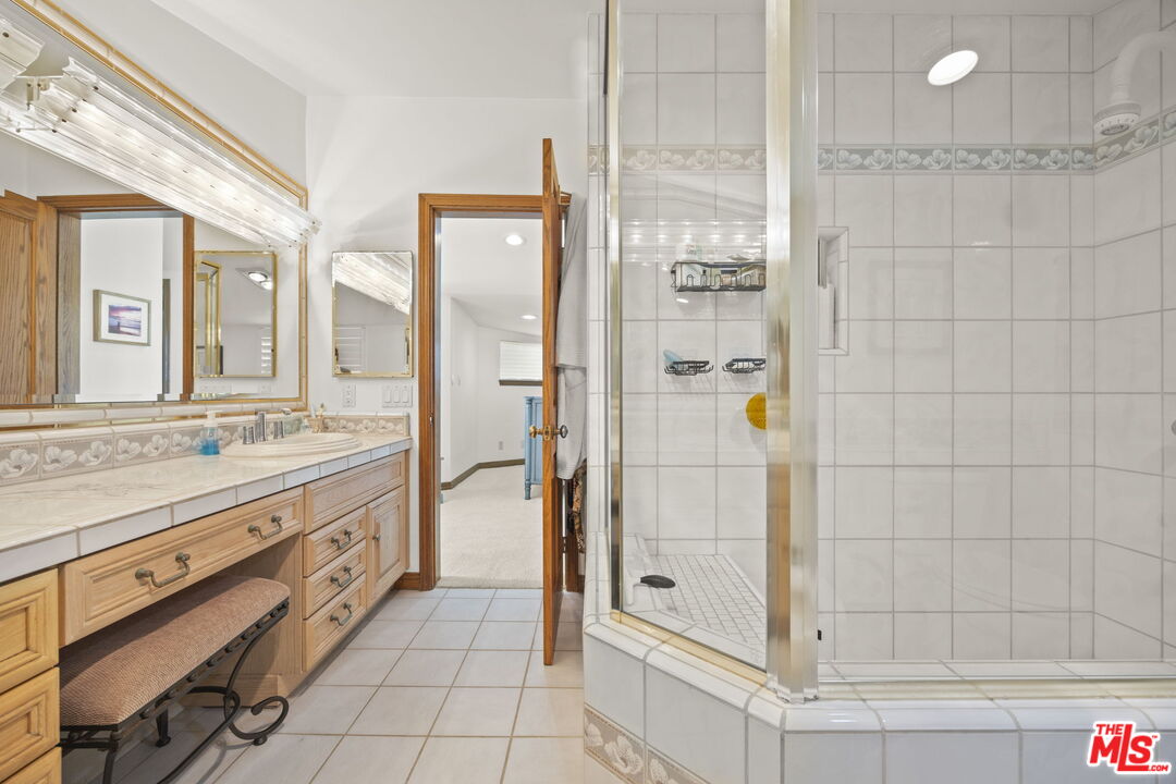 1005 Ocean Drive Oxnard, CA 93035 - Photo 23 of 56 a bathroom with a granite countertop shower a mirror and a sink