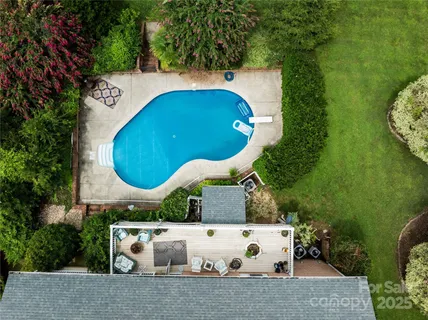 an aerial view of a house with swimming pool and large trees