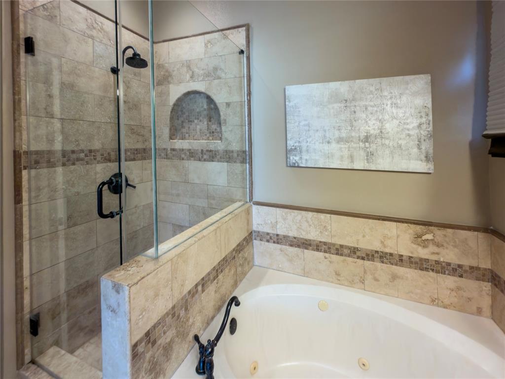 4234 Timberglen Road Dallas, TX 75287 - Photo 19 of 32 Walk-in shower with clear glass enclosure and tile surround featuring a decorative mosaic band and integrated niche