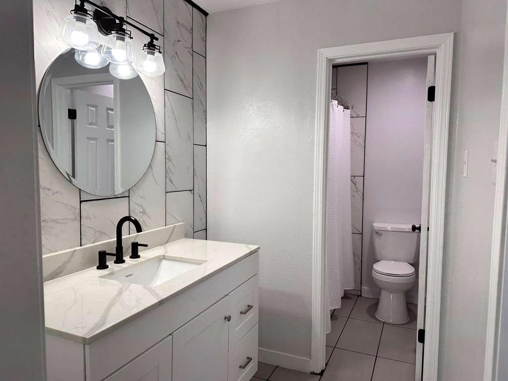 10526 Stone Canyon Road, Unit 201 Dallas, TX 75230 - Photo 12 of 21 a bathroom with a sink a toilet and a mirror