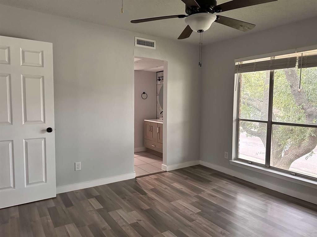 10526 Stone Canyon Road, Unit 201 Dallas, TX 75230 - Photo 15 of 21 an empty room with wooden floor a ceiling fan and windows