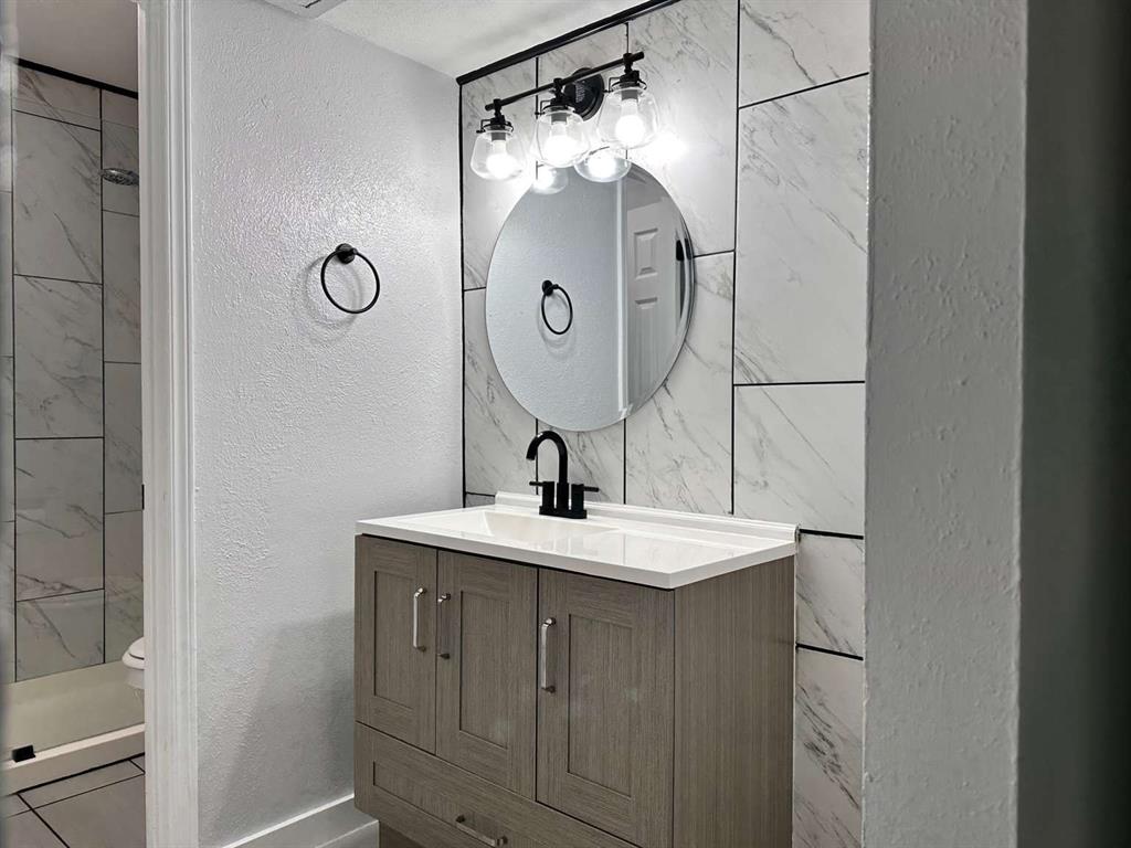10526 Stone Canyon Road, Unit 201 Dallas, TX 75230 - Photo 16 of 21 a bathroom with a sink a mirror and a shower