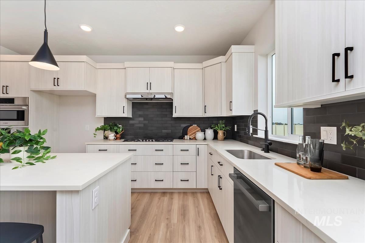 2829 West Warlander Street Meridian, ID 83642 - Photo 11 of 32 Kitchen with stainless steel dishwasher, light wood-style floors, hanging light fixtures, light stone counters, and modern cabinets