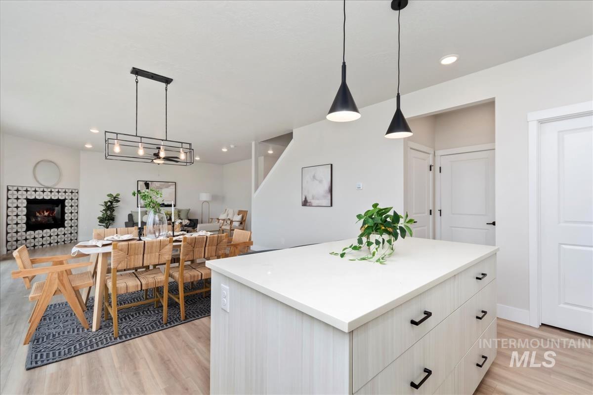 2829 West Warlander Street Meridian, ID 83642 - Photo 12 of 32 Kitchen with a center island, hanging light fixtures, light wood finished floors, white cabinetry, and a fireplace