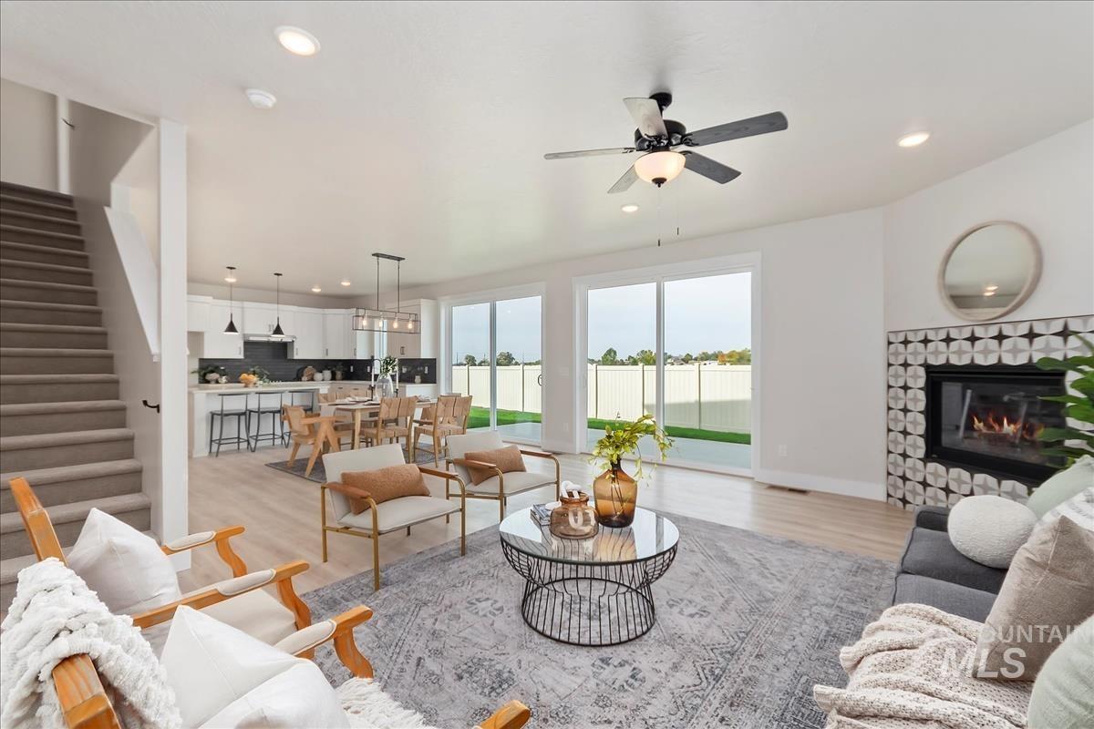 2829 West Warlander Street Meridian, ID 83642 - Photo 3 of 32 Living area with light wood-style flooring, a stone fireplace, a ceiling fan, and recessed lighting