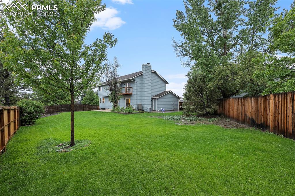 9054 Estebury Circle Colorado Springs, CO 80920 - Photo 21 of 26 a backyard of a house with plants and large tree