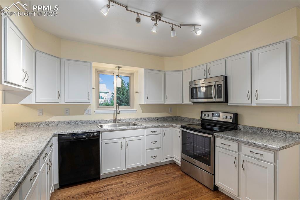 9054 Estebury Circle Colorado Springs, CO 80920 - Photo 5 of 26 a kitchen with stainless steel appliances granite countertop white cabinets granite counter tops and a hard wood floors