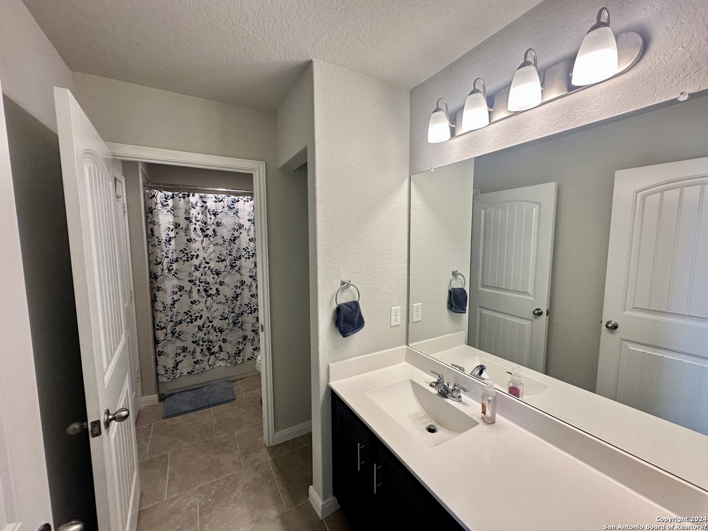 8907 Portobello Converse, TX 78109 - Photo 19 of 26 a en suite bathroom with a double vanity sink a mirror and shower