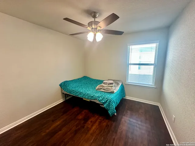 a room with wooden floor fan and windows