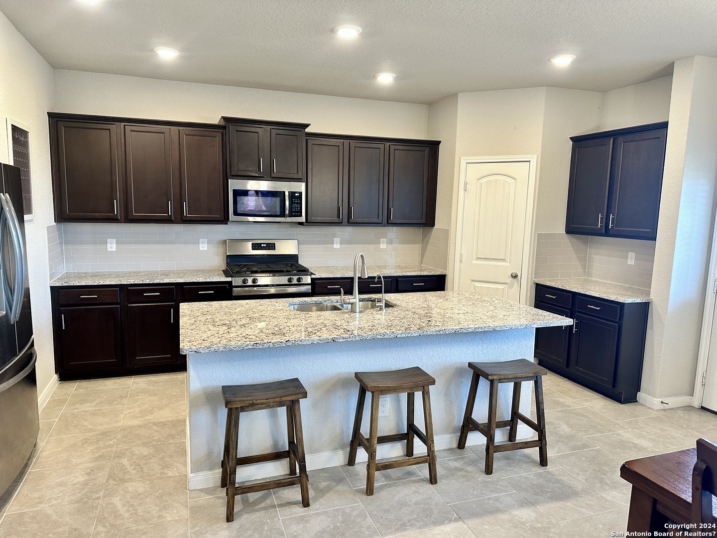 8907 Portobello Converse, TX 78109 - Photo 4 of 26 a kitchen with granite countertop a stove top oven a sink a dining table and chairs