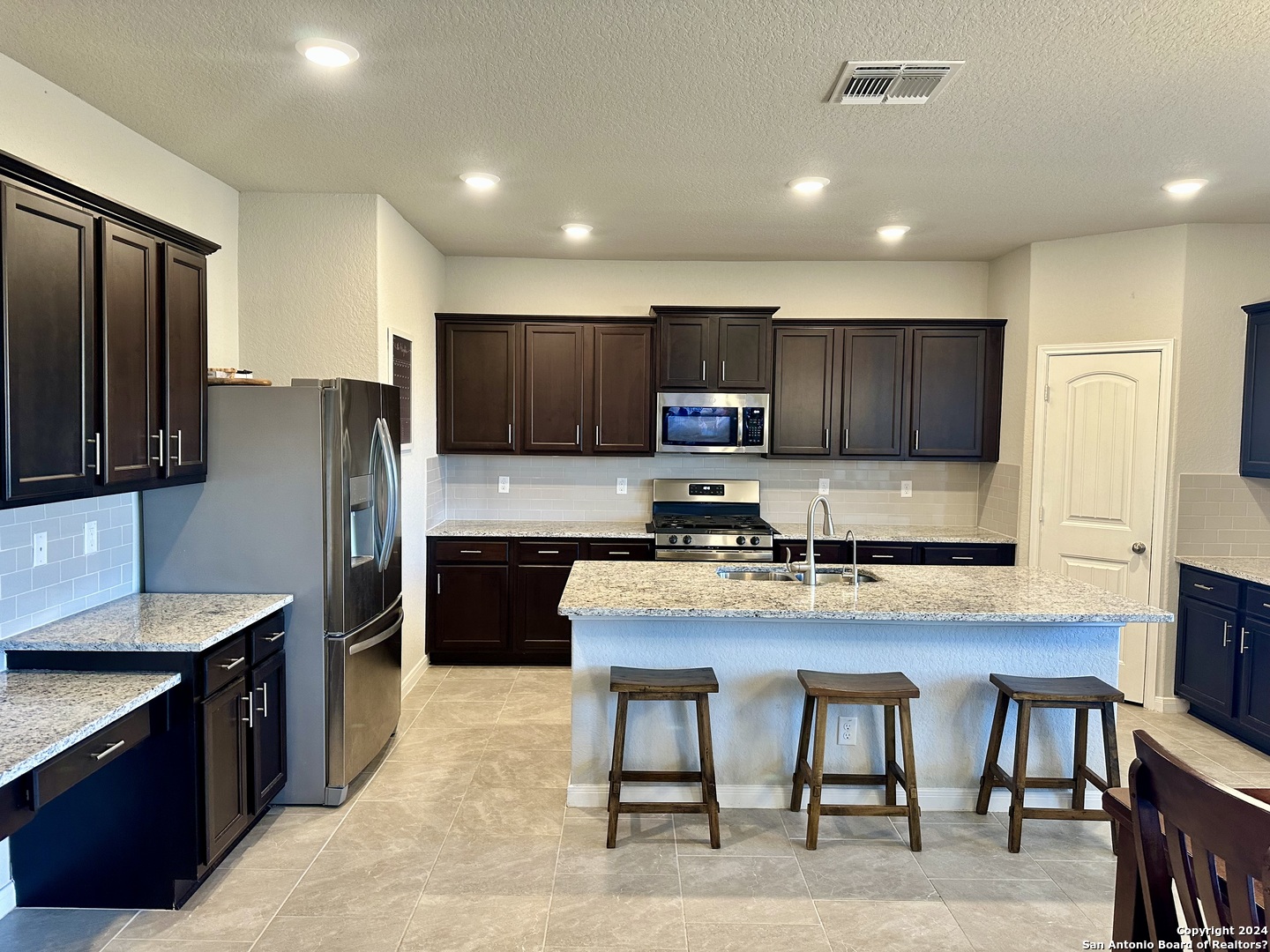 8907 Portobello Converse, TX 78109 - Photo 5 of 26 a kitchen with kitchen island granite countertop wooden cabinets and refrigerator