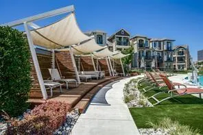 a view of a tall white building with a yard and potted plants