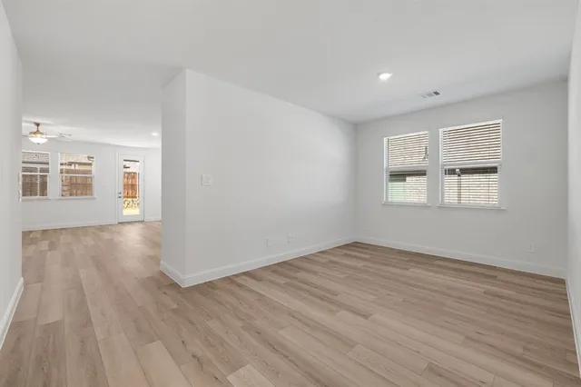an empty room with wooden floor and windows