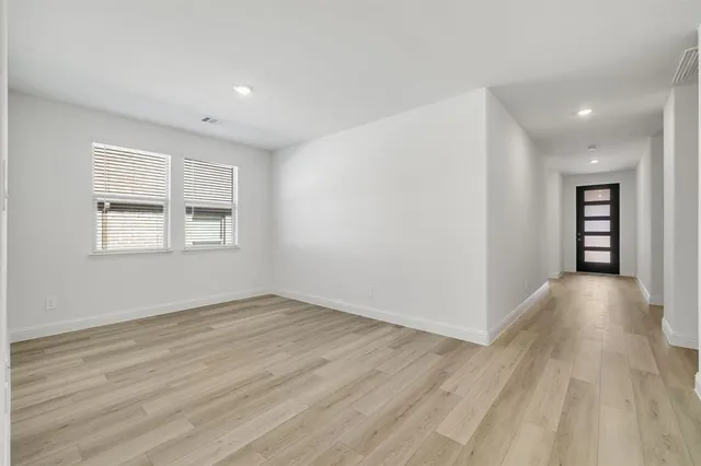 a view of an empty room with a kitchen and a window