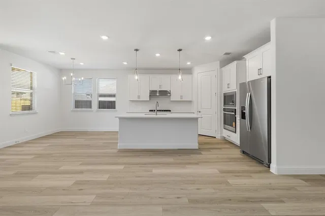 a large kitchen with stainless steel appliances granite countertop a stove a sink and a refrigerator