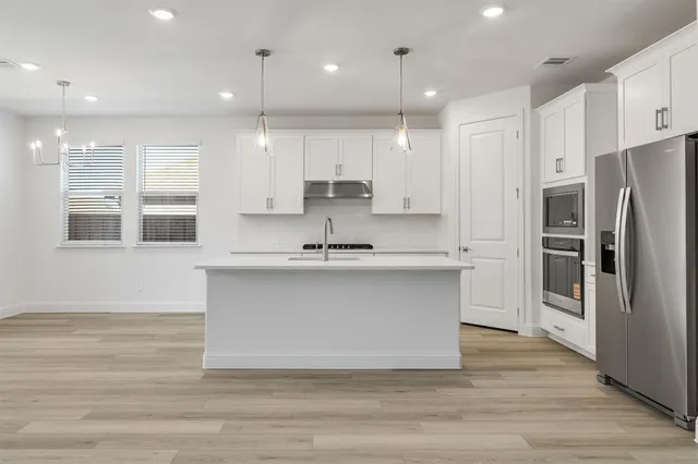 a view of a kitchen with a sink and dishwasher a refrigerator with wooden floor