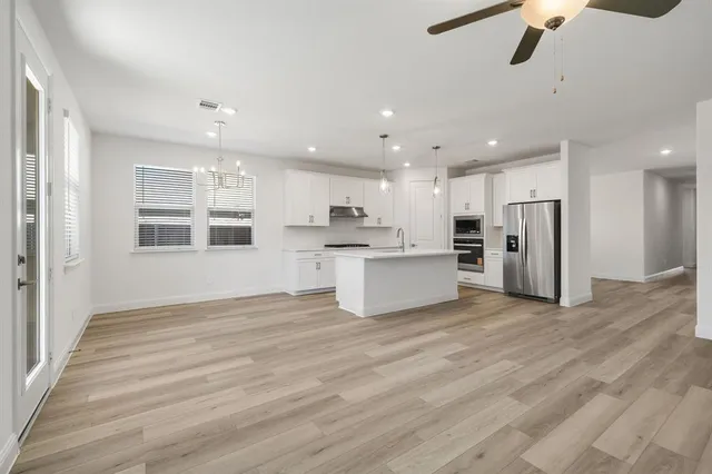 a large kitchen with stainless steel appliances granite countertop a stove a sink and a refrigerator