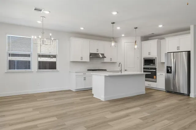 a kitchen with stainless steel appliances granite countertop a refrigerator a stove oven and white cabinets