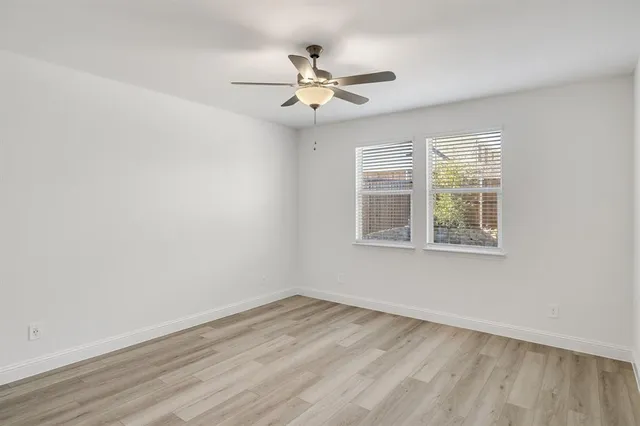 an empty room with wooden floor and ceiling fan