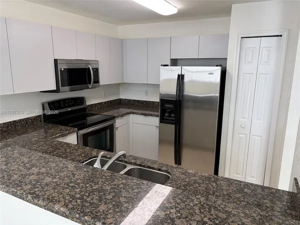 a kitchen with a refrigerator and a stove top oven